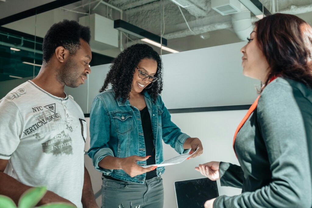 Three adults engaging in a business discussion in a bright, modern office setting.